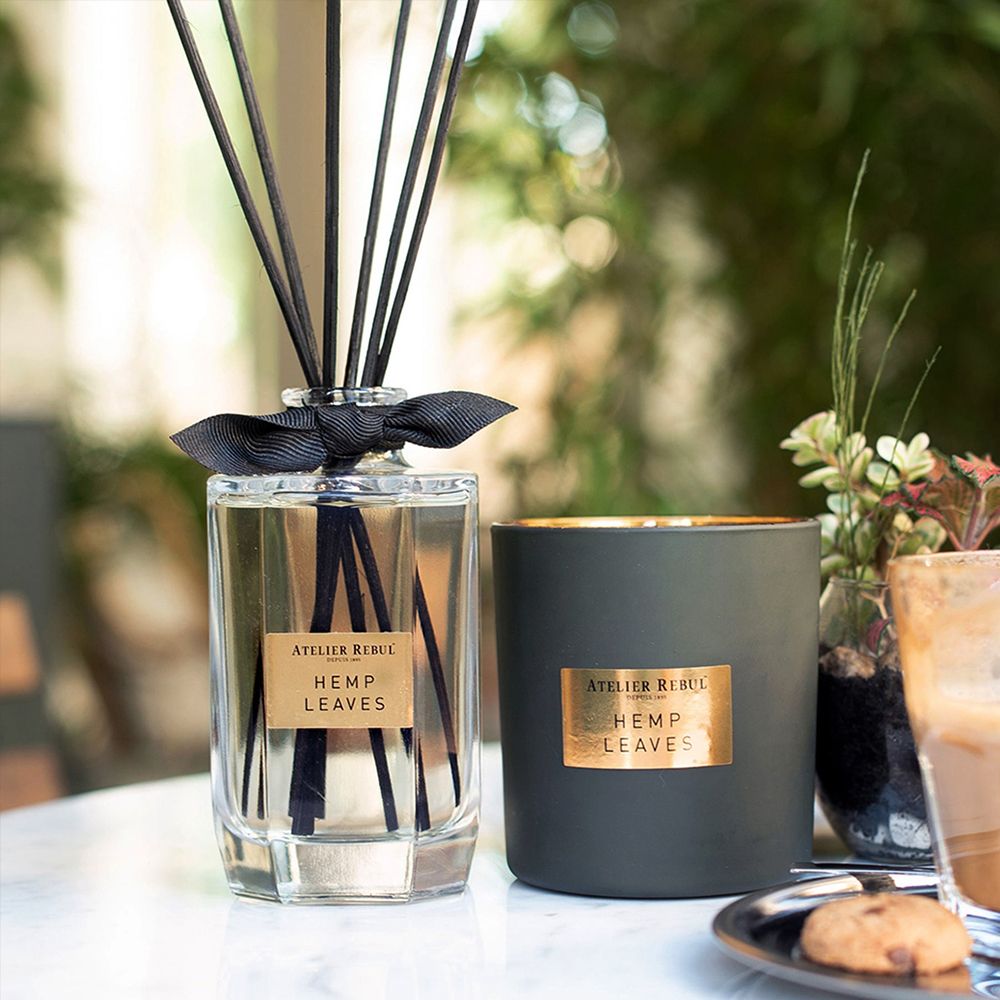 ATELIER REBUL® Reed Diffusor und Kerze. Auf Tisch. Diffusor mit Stäbchen, Kerze und Glas.