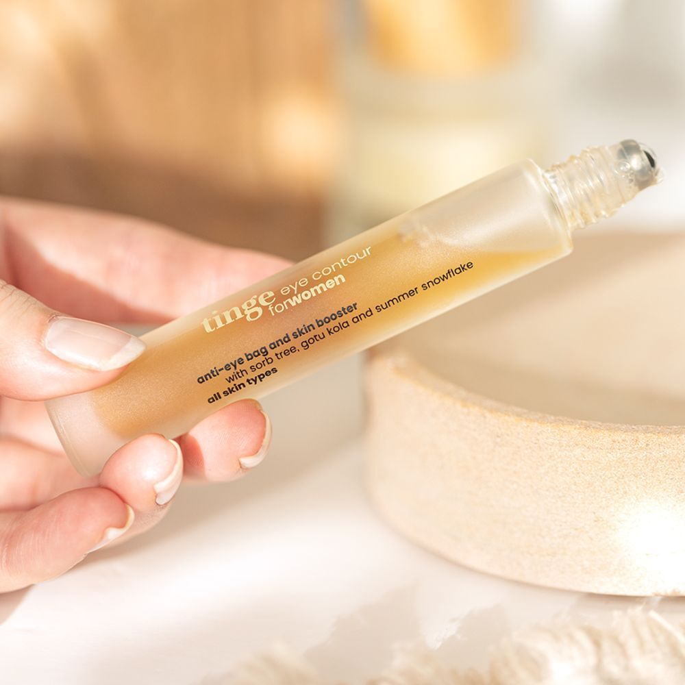 Tinge Eye Contour voor vrouwen. Roll-on applicator in een hand. Product met ingrediënten zoals Gotu Kola en sneeuwvlok.