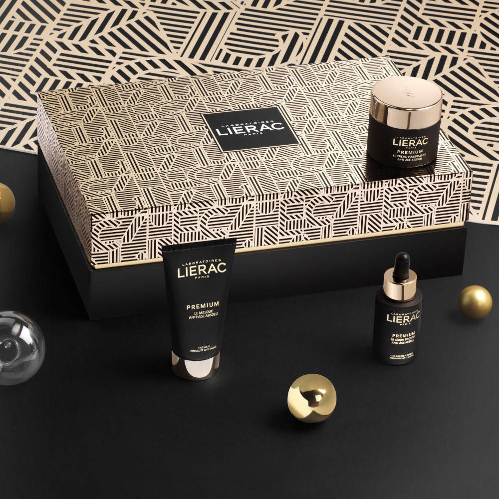 Zwarte achtergrond met cosmetische producten. Crème, serum en tube. Gouden ballen als decoratie. Tekst: Lierac Premium Anti-Aging Global.