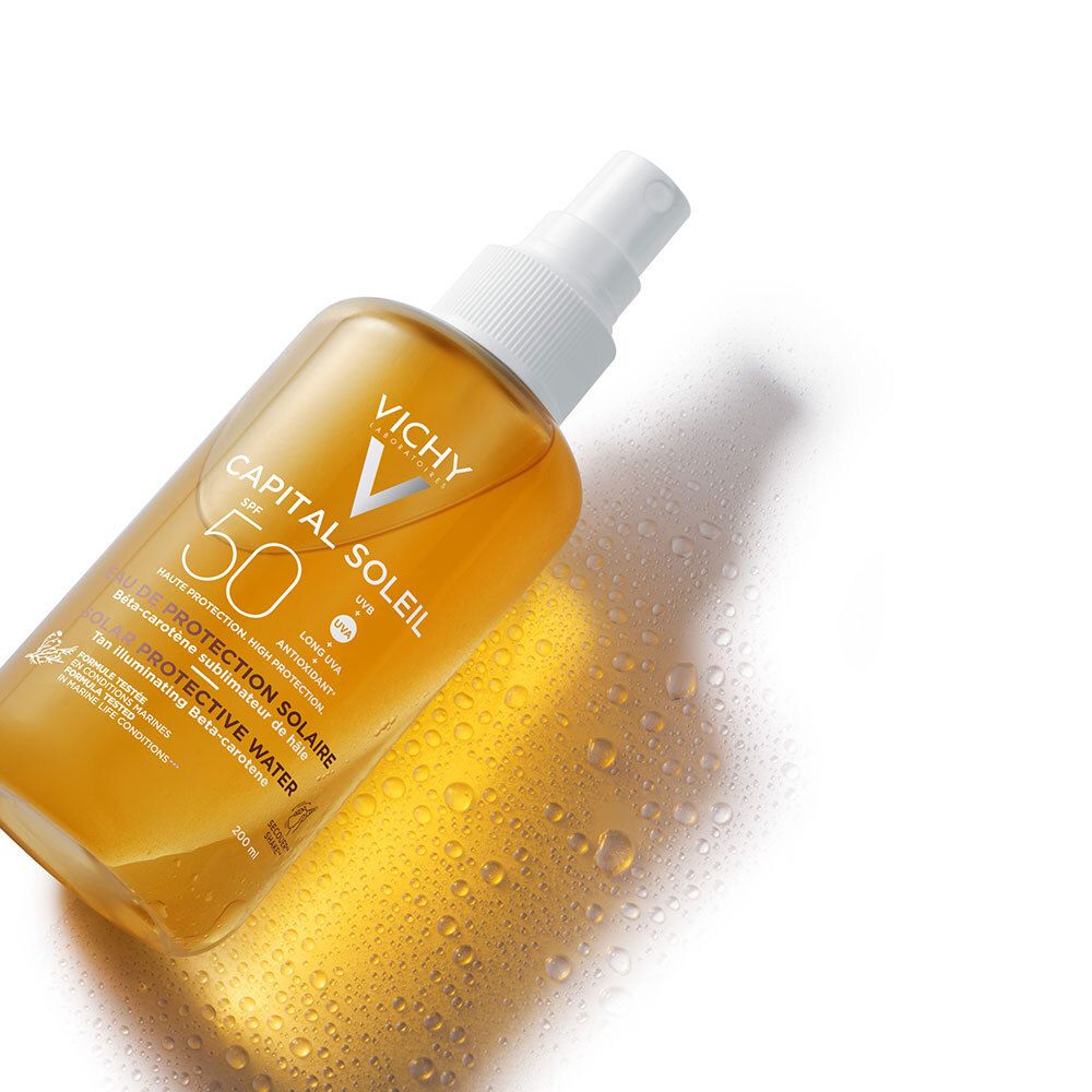 Flacon Vichy Capital Soleil Eau de protection solaire SPF50. Gros plan avec gouttes d'eau.