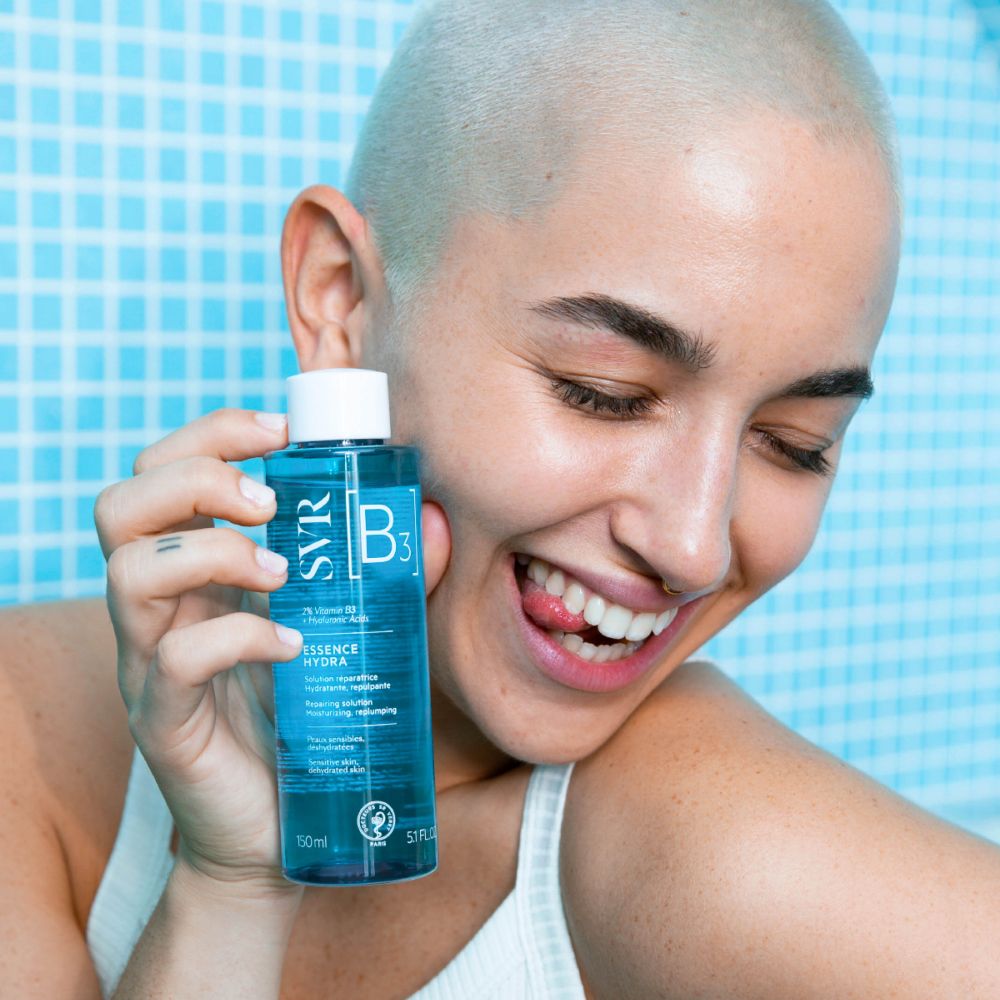 Flacon bleu avec bouchon blanc. Inscription : SVR [B3] ESSENCE HYDRA. Contient 2% Vitamine B3 + Acide Hyaluronique. Pour peaux sensibles, déshydratées.