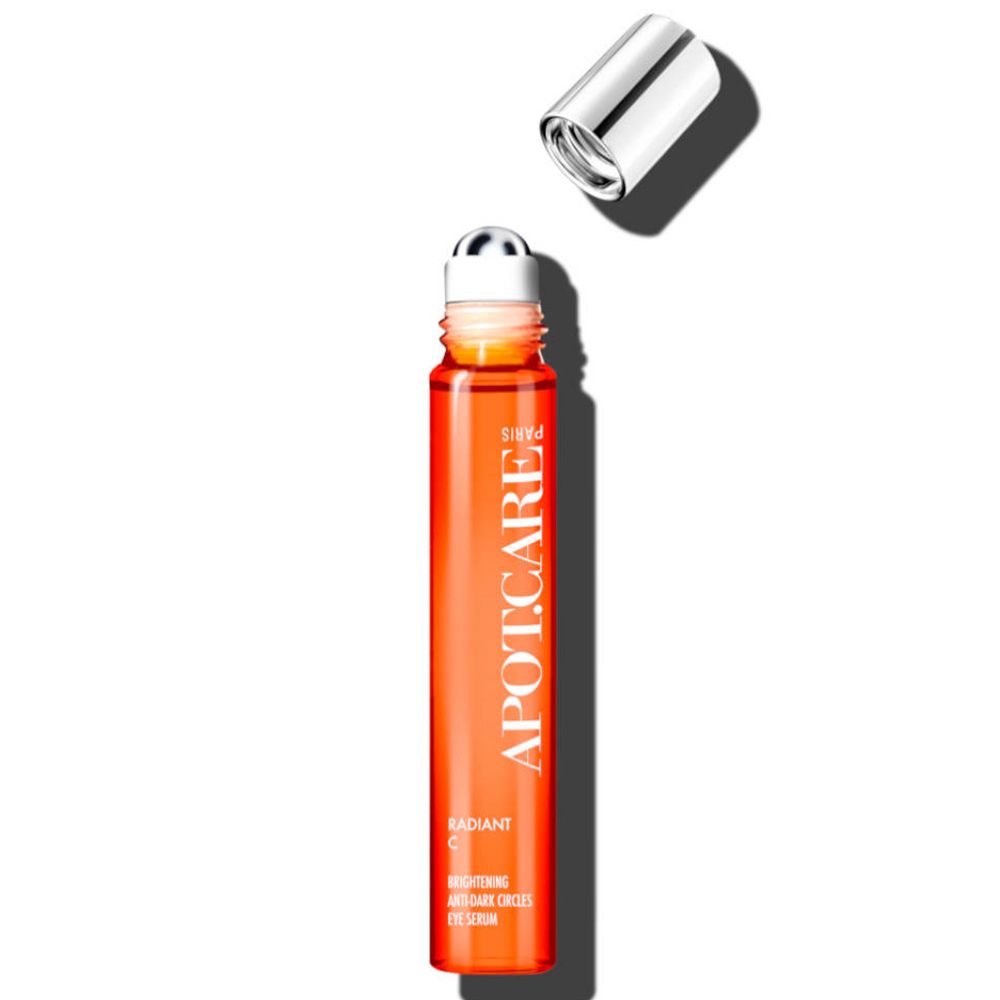 Flacon cylindrique APOT.CARE avec bouchon argenté. Applicateur à bille. Liquide orange. Inscription: Radiant C Eye Serum. 