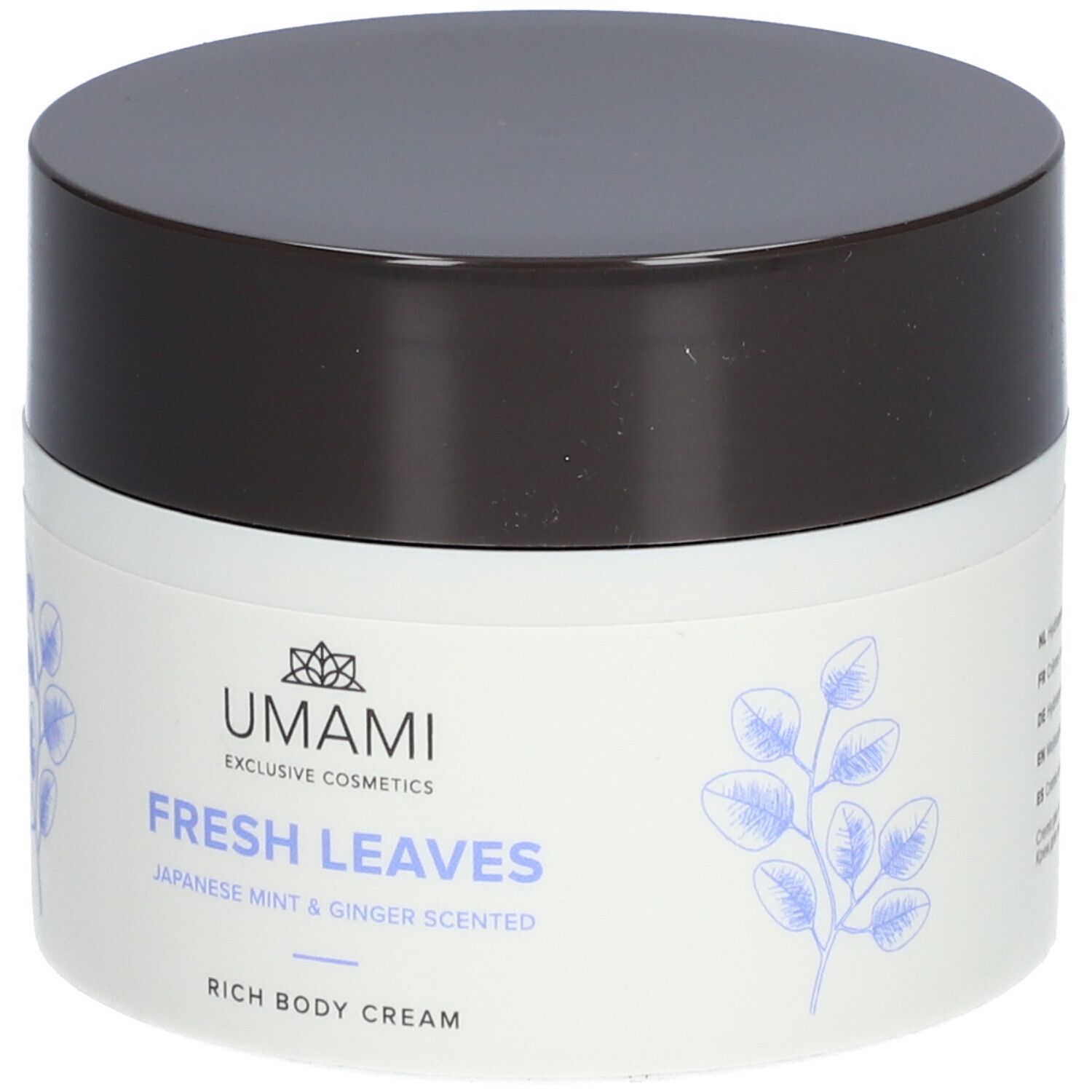 Weißer Tiegel mit braunem Deckel. Aufschrift: UMAMI, FRESH LEAVES, Japanese Mint & Ginger Scented, Rich Body Cream. Blätter-Dekor.