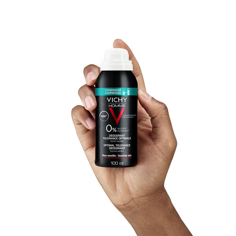 Persoon houdt deodorant sprayfles vast. Zwarte fles, witte sproeikop. Tekst: Vichy Homme, 48H, 0% alcohol.