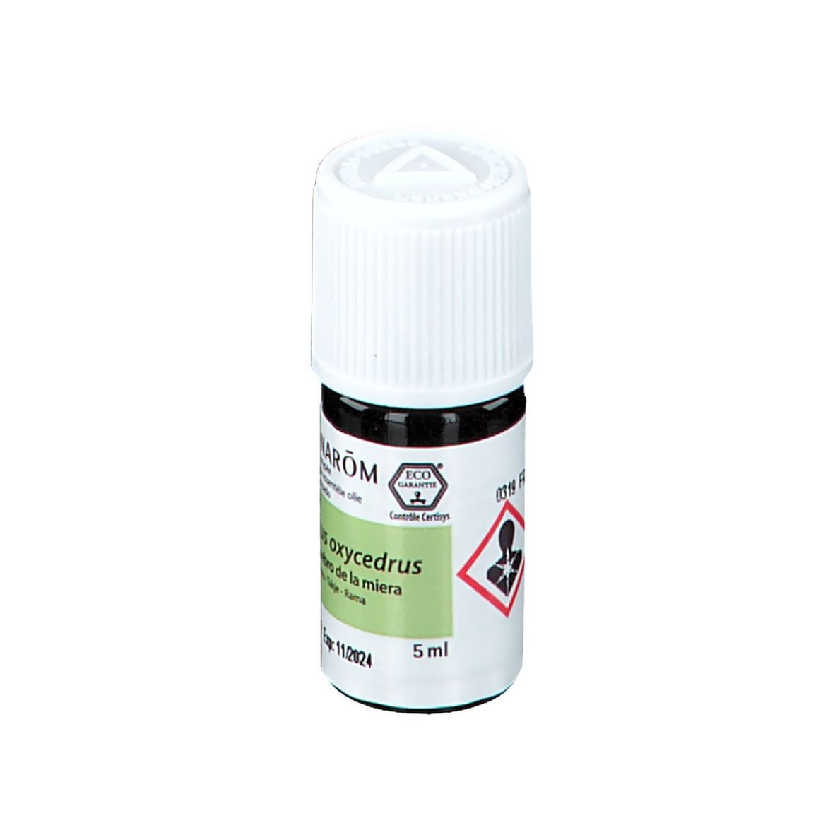 Bouteille en verre brun avec bouchon blanc. Étiquette avec nom du produit, nom botanique, 5 ml et symboles de danger.
