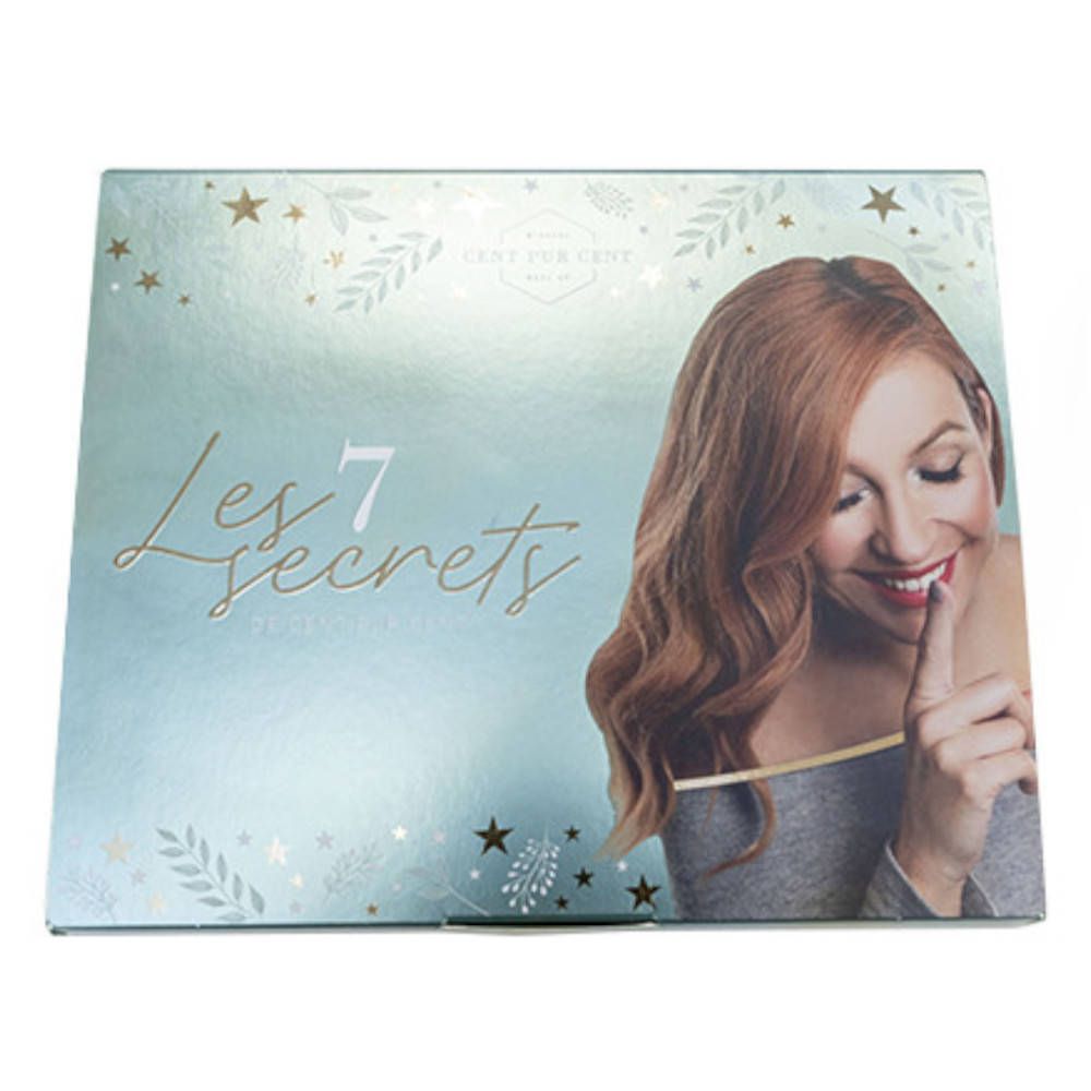 Boîte avec inscription "Les 7 secrets". Femme avec un doigt sur les lèvres. Étoiles et feuilles décoratives.