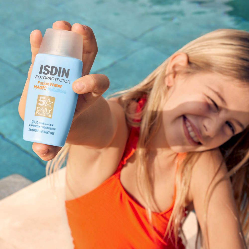 Ein Mädchen hält eine ISDIN Fotoprotector Pediatrics Fusion Water MAGIC Sonnencreme in der Hand.