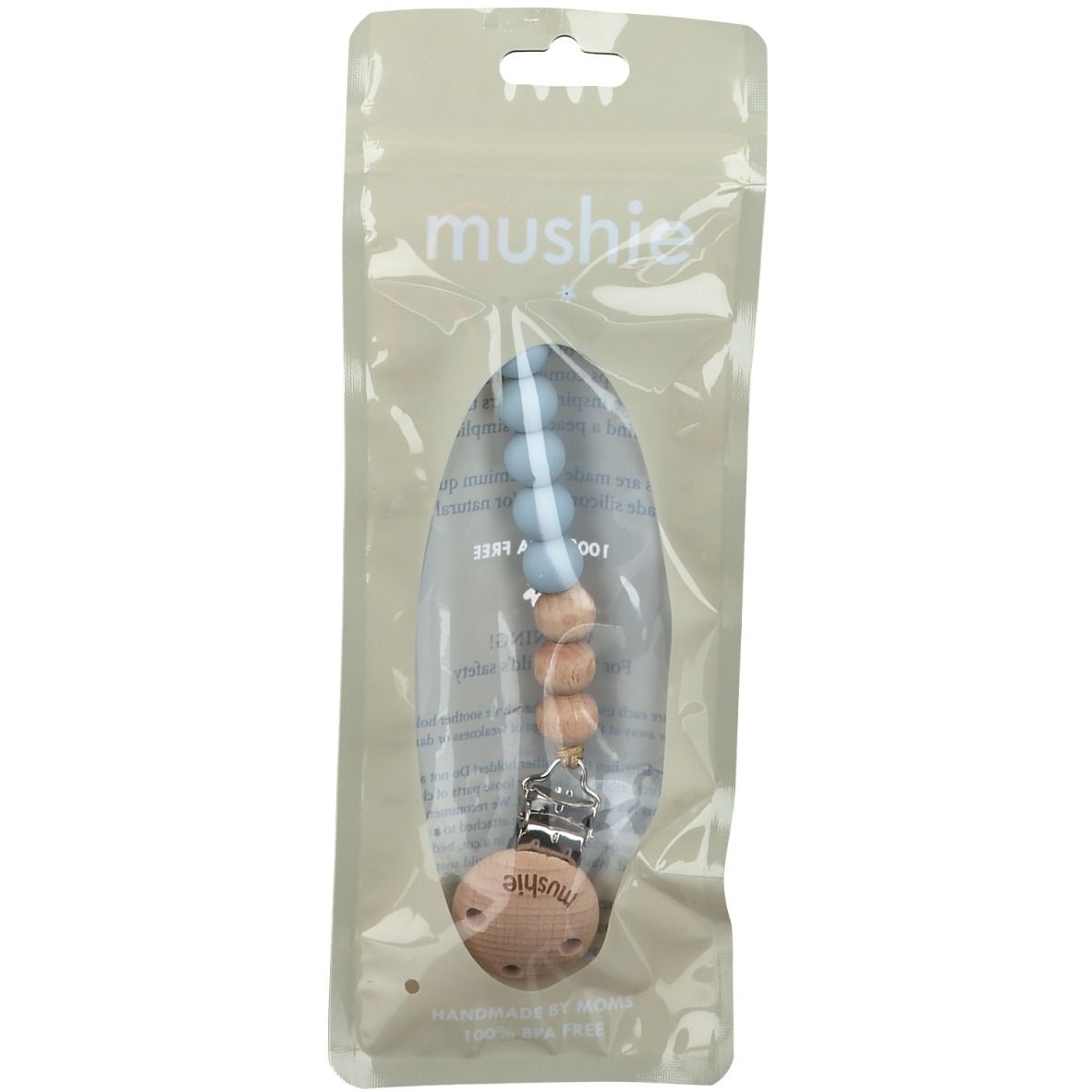 Schnullerkette in transparenter Verpackung. Holz- und blaue Silikonperlen, Holzclip. Marke: mushie. "HANDMADE BY DESIGN".