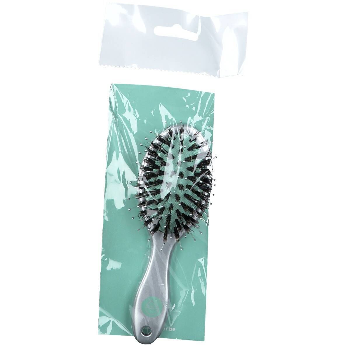 Brosse à cheveux dans un emballage transparent. Tête de brosse ovale avec poils et manche. Sur fond vert clair.
