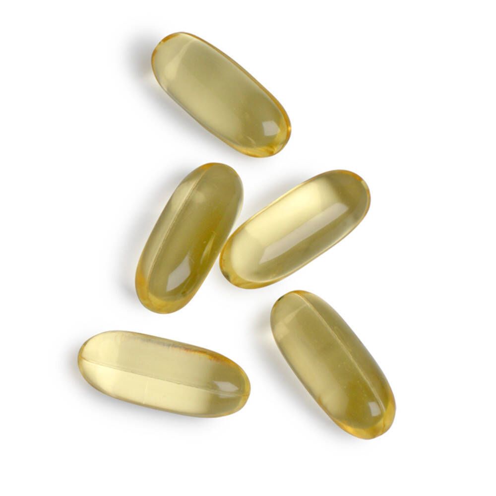 Vijf gele, ovale capsules op witte achtergrond.