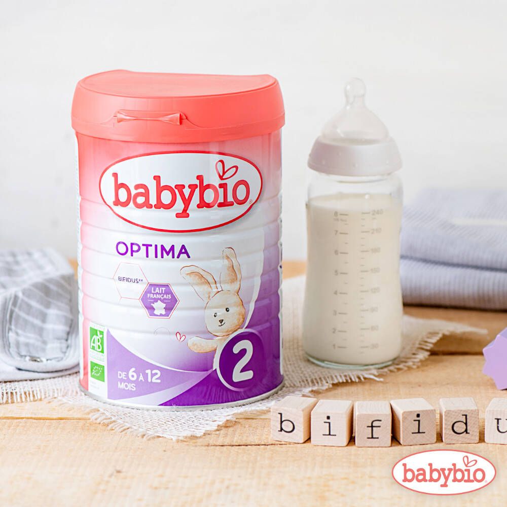Boîte Babybio Optima 2 et biberon de lait. Fond en bois. Cubes de lettres.