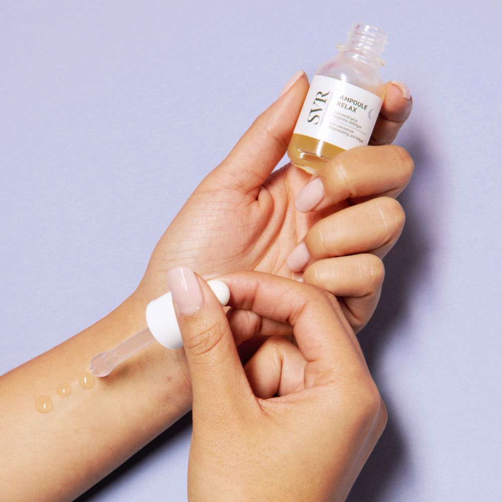 Mains tenant un flacon de sérum avec pipette. Inscription : SVR, Ampoule Relax.