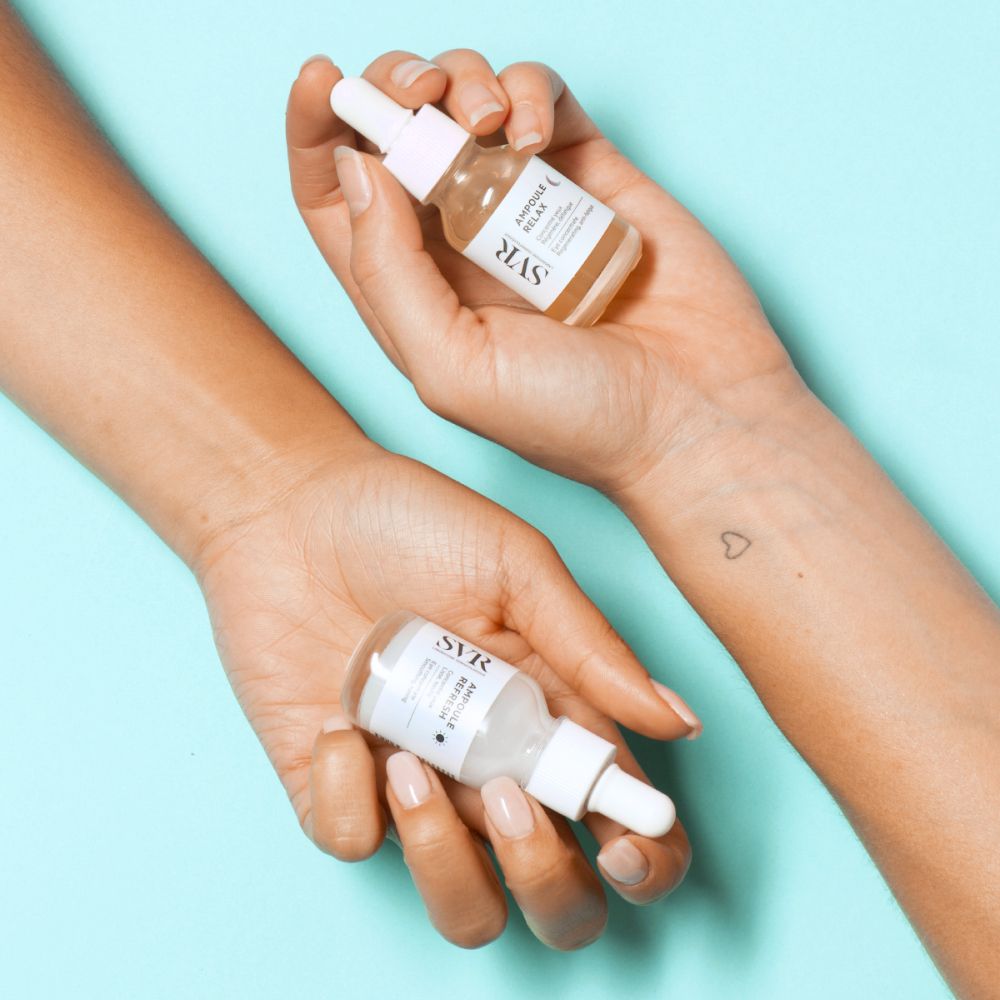 Mains tenant des flacons de sérum avec pipettes. Inscription : SVR, Ampoule Relax.