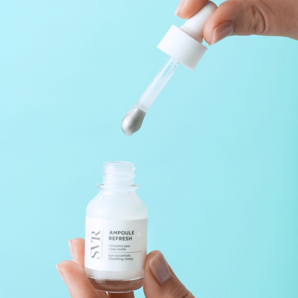 Mains tenant un flacon et une pipette. La pipette verse du liquide dans le flacon. SVR AMPOULE REFRESH.