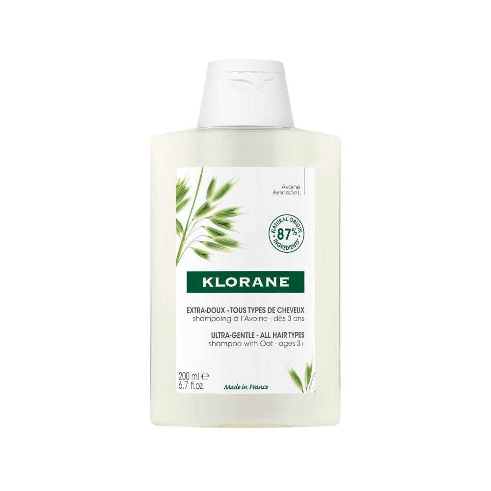 Flacon de shampooing Klorane. Design rectangulaire blanc avec bouchon blanc. Étiquettes vertes et blanches avec informations et logo.