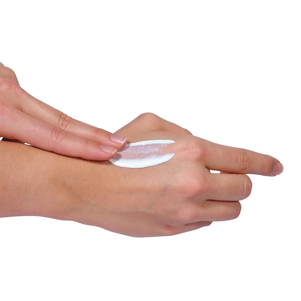 Hand met aangebrachte zonnebrandmelk. Witte crème op de huid. Vingers raken de crème aan.