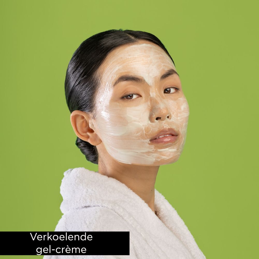 Vrouw met gezichtsmasker. Crème-gel textuur op gezicht, witte handdoek, groene achtergrond.