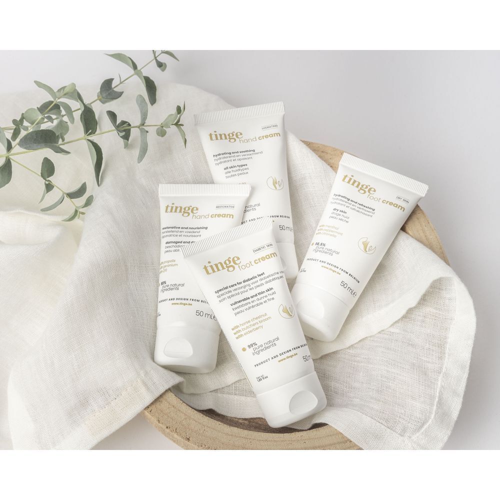 Vier tubes voetcrème in een mandje op een doek. Productnaam en informatie zichtbaar.
