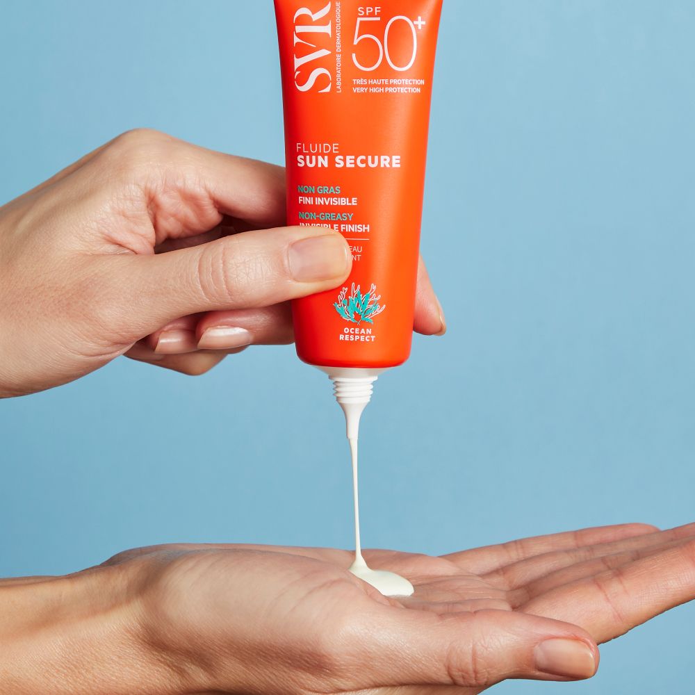 Een hand drukt een witte vloeistof uit een oranje tube.