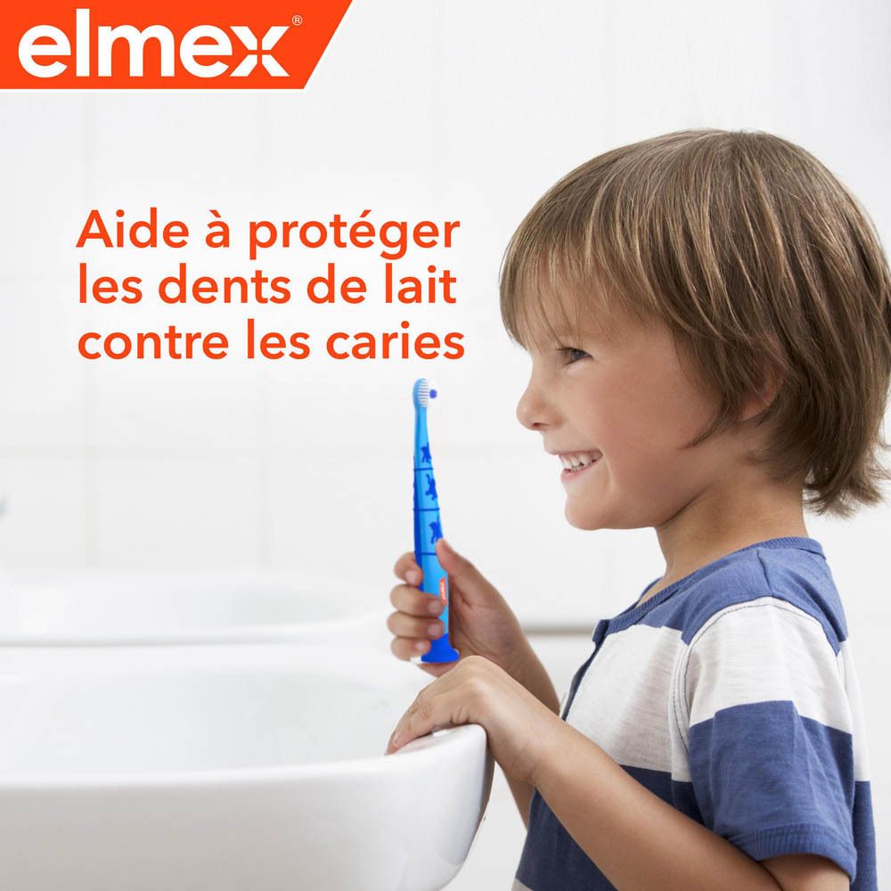 Enfant tenant une brosse à dents elmex® bleue. Texte : Aide à protéger les dents de lait contre les caries.