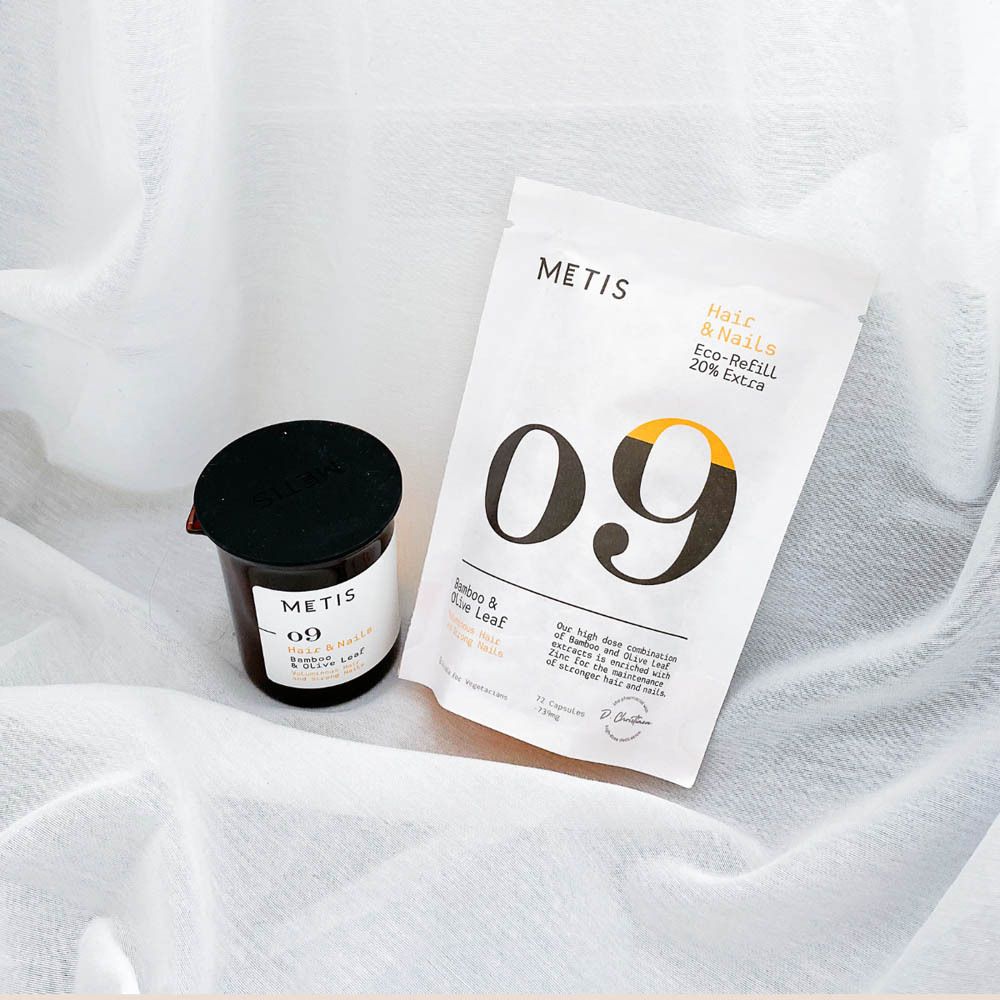Potje en zak met "09". "METIS" logo en productinformatie. Gedrapeerd op witte stof.