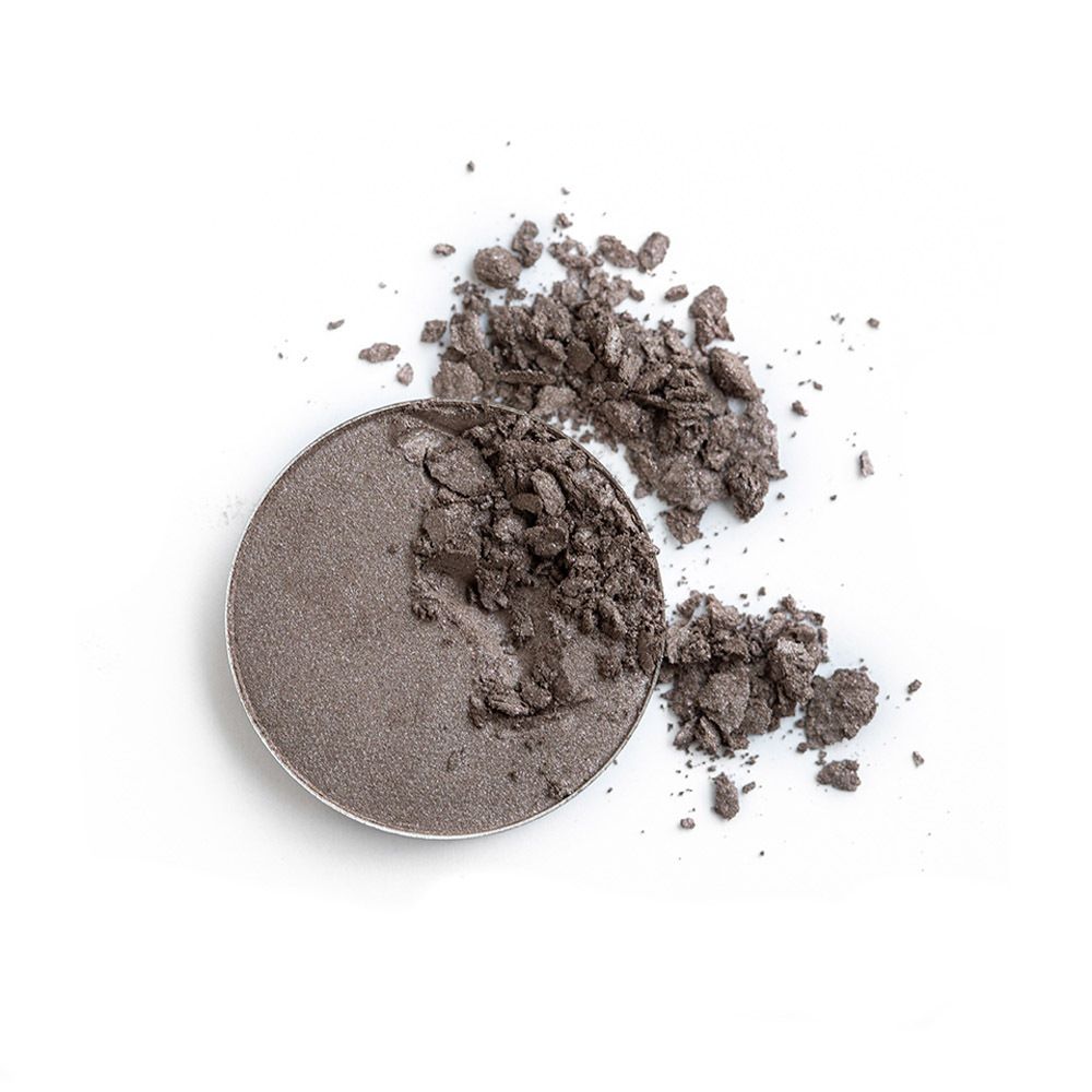 Fard à paupières rond et cassé gris sur fond blanc.