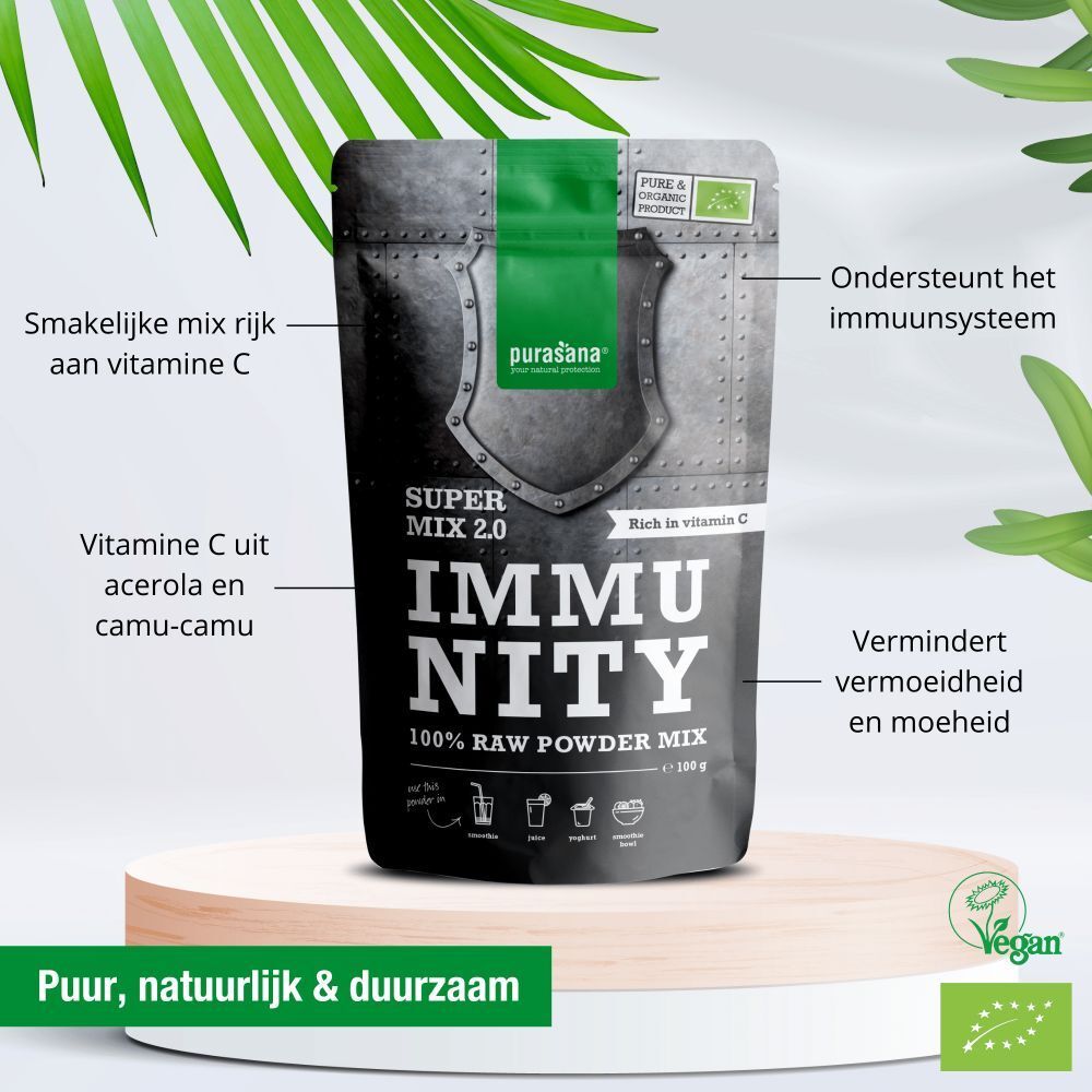 Productverpakking "IMMUNITY" poeder. Witte en groene tekst. Bevat vitamine C. Vegan label. Op een sokkel met bladeren.
