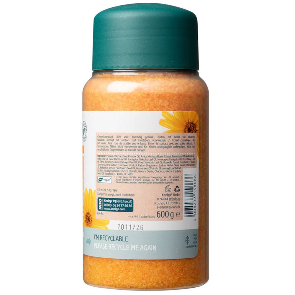 Dos d'un flacon transparent de cristaux de bain orange. Bouchon vert. Étiquette avec texte et ingrédients.
