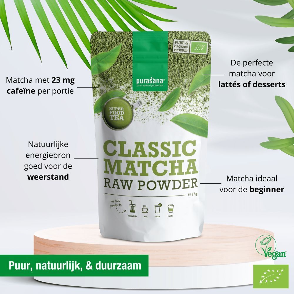 Verpakking Classic Matcha Raw Powder. Tekst: Matcha met 23 mg cafeïne per portie. Vegan-keurmerk. Op voetstuk met bladeren.