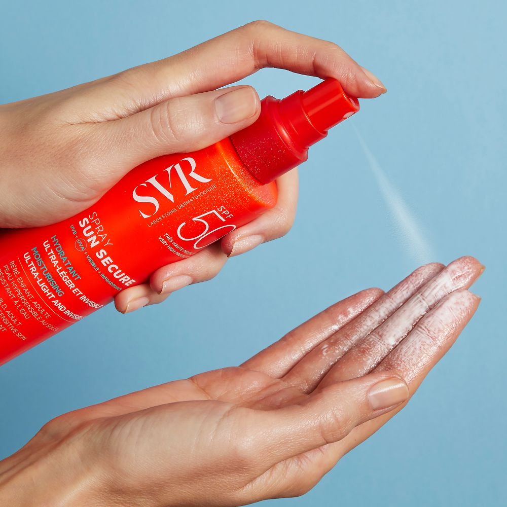 Mains se pulvérisant de crème solaire. Flacon orange avec tête rouge. Inscriptions : SVR, SUN SECURE.