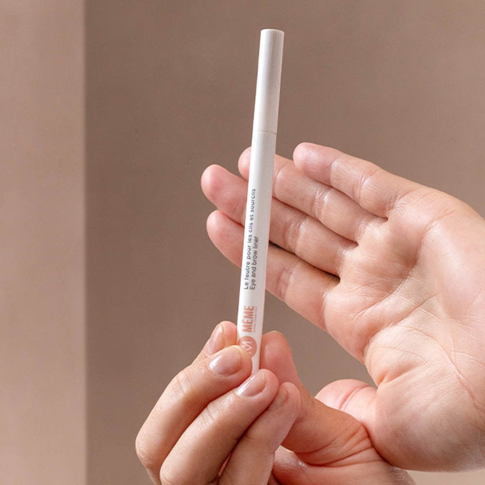 Mains tenant le feutre MÊME pour sourcils. Blanc, fin. Eye and brow liner. Présentation produit.