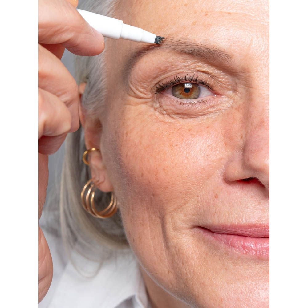 Gros plan : personne dessine sourcil avec feutre MÊME. Eye and brow liner. Application.