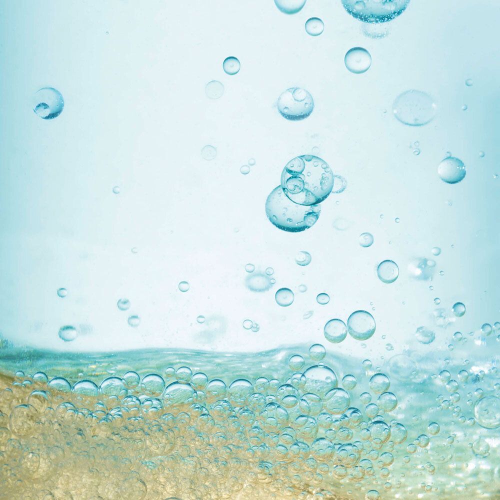 Gros plan de bulles dans un liquide. Tons jaunâtres et bleus.