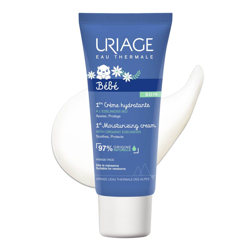 Tube bleu avec bouchon blanc. Inscription: URIAGE Bébé, 1re Crème hydratante, 97% origine naturelle. Éclaboussure de crème.
