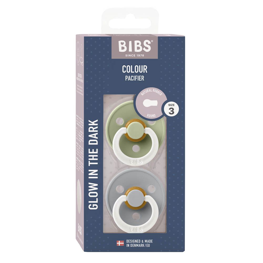 Verpakking met twee fopspenen. BIBS-logo, 'COLOUR PACIFIER', 'GLOW IN THE DARK'. Maat 3.