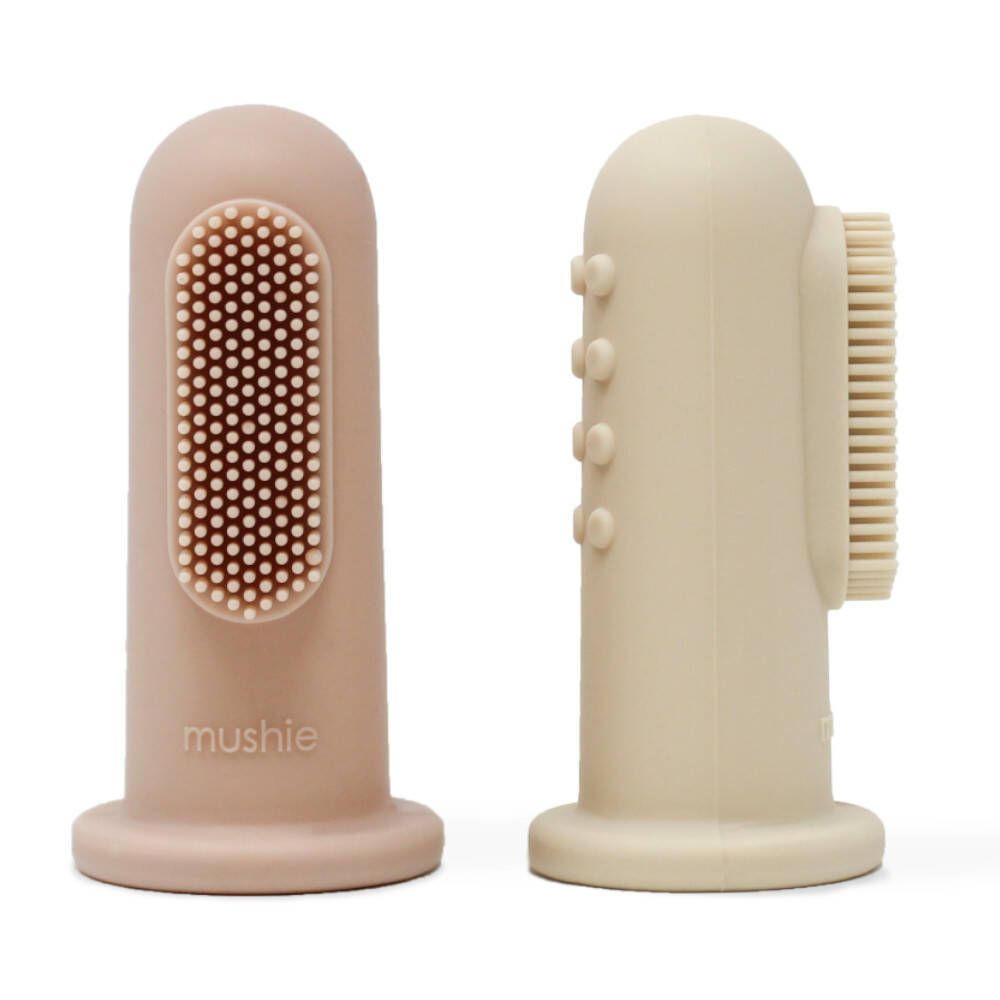 Zwei Fingerzahnbürsten. Eine rosa, eine beige. Beide haben Borsten. Aufschrift: mushie.