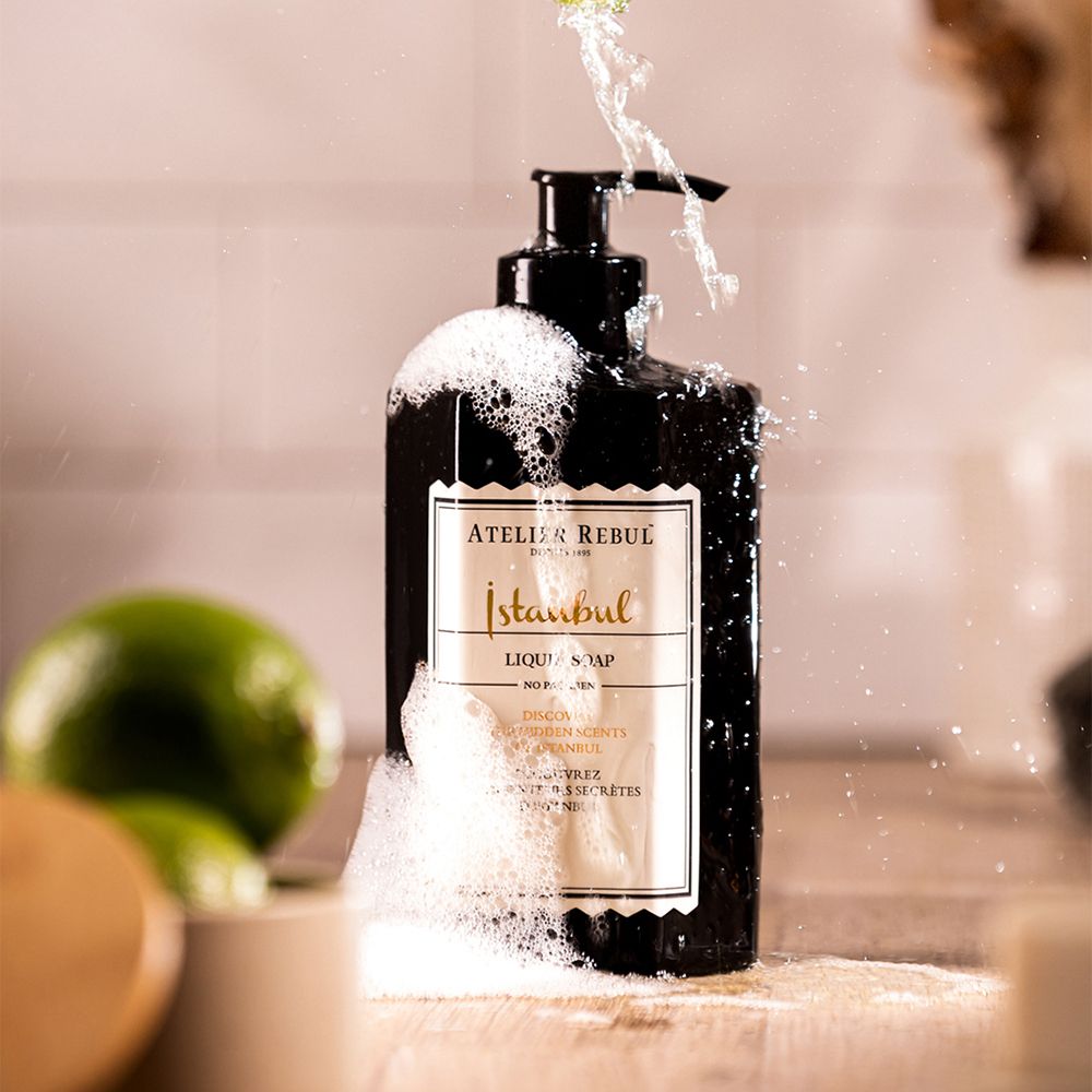 Schwarze Flüssigseifenflasche mit Schaum und Limetten. Aufschrift: ATELIER REBUL Istanbul Liquid Soap.