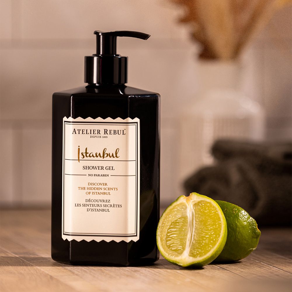 Zwarte fles met doseerpomp, naast limoenen. Opschrift: Istanbul Shower Gel, Atelier Rebul.