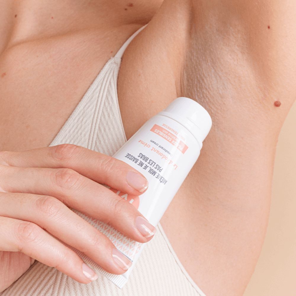 Persoon houdt crème deodorant tube vast. Toepassing onder de arm. Huid zichtbaar.