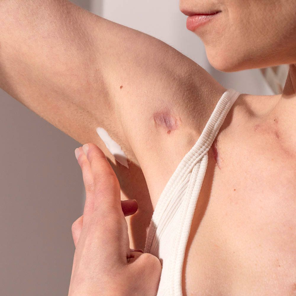 Persoon brengt crème deodorant aan. Toepassing onder de arm. Huid zichtbaar.