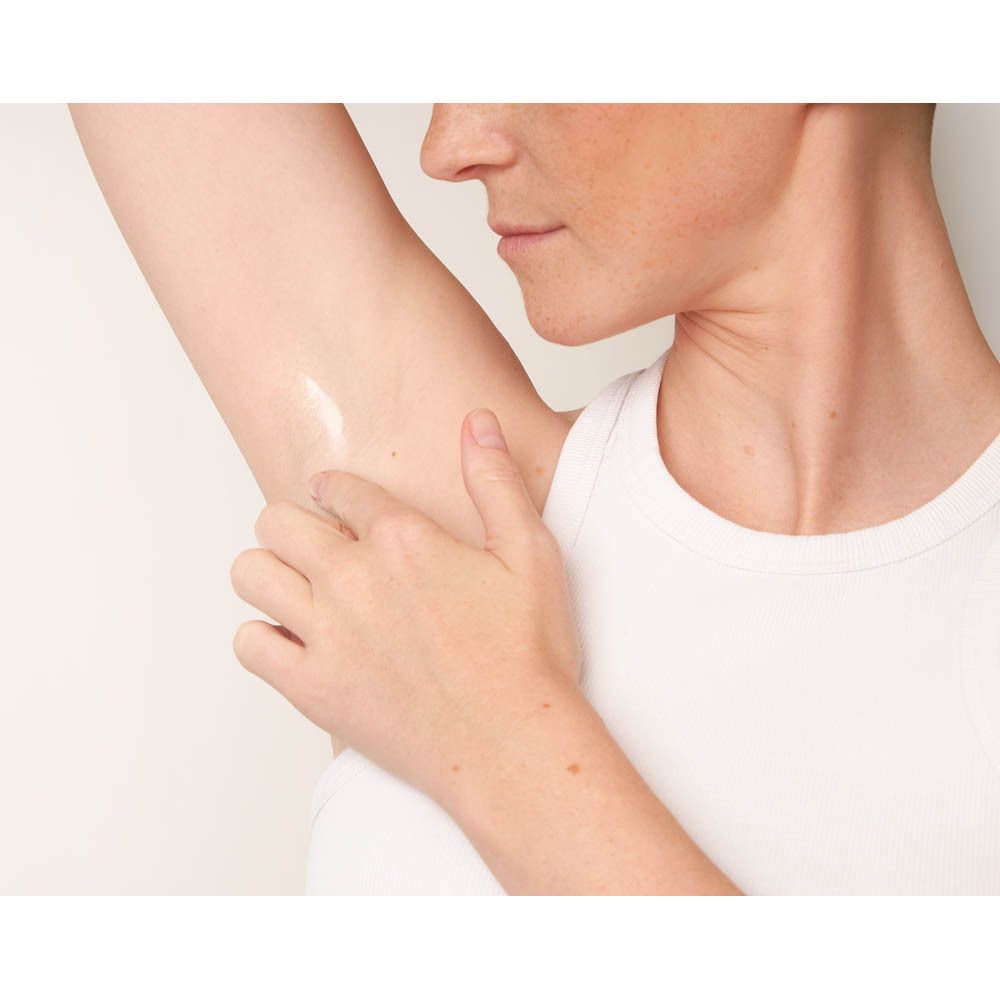 Persoon brengt crème deodorant aan. Toepassing onder de arm. Huid zichtbaar.