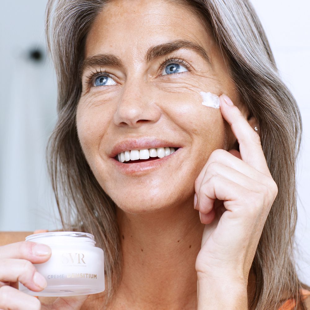 Vrouw brengt crème aan. Op de pot staat "SVR" en "CREME DENSITIUM".