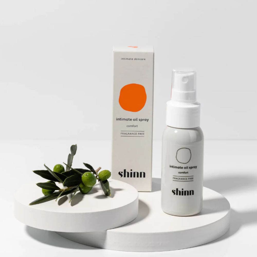 Spray blanc, boîte, branche d'olivier. Inscription : intimate oil spray comfort. Marque : shinn. Avec olives.