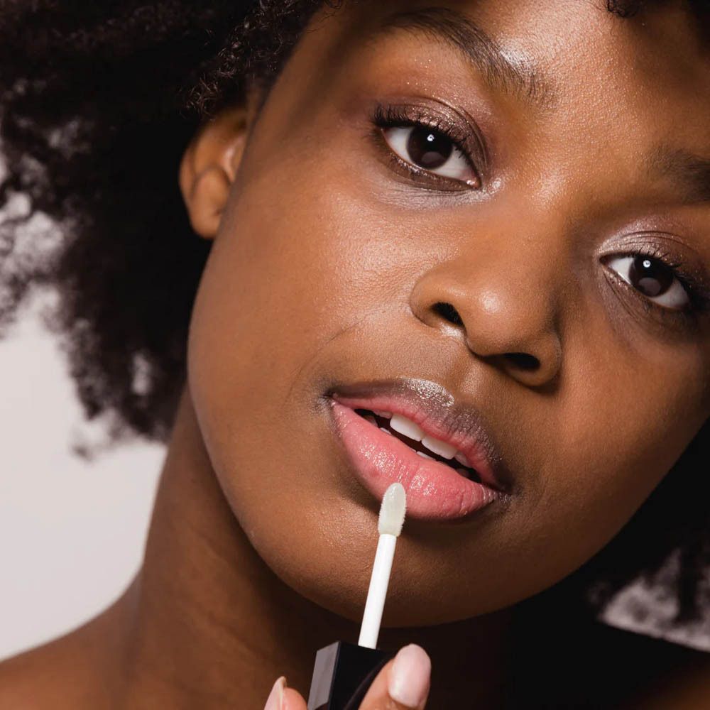 Vrouw brengt lipgloss aan met applicator.