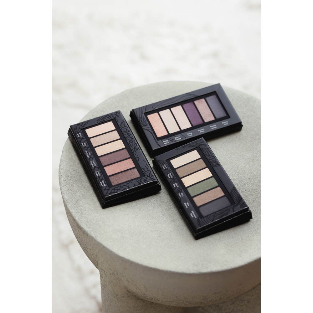 Trois palettes de fards à paupières sur une surface. Les palettes avec six teintes sont présentées.