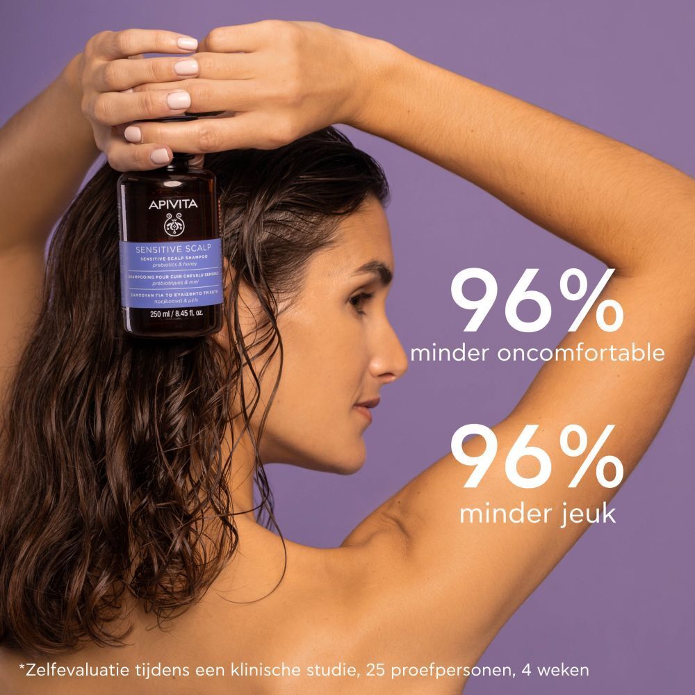 Vrouw houdt fles vast. Tekst: APIVITA, Sensitive Scalp Shampoo, 250 ml. 96% minder oncomfortabel.