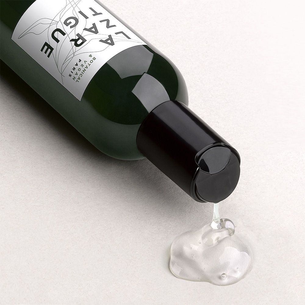 Groene fles, zwarte dop, product wordt uitgegoten. Heldere vloeistof.