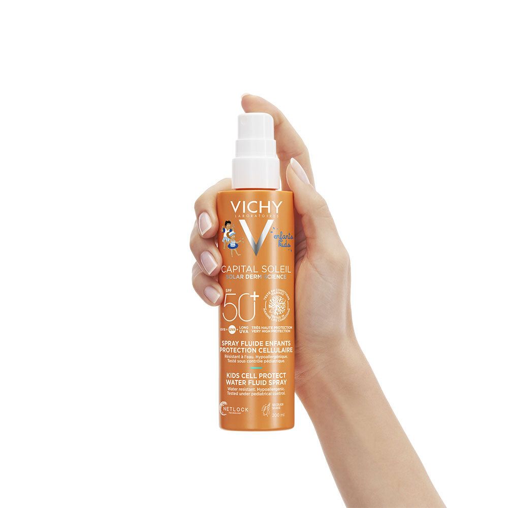 Main tenant un flacon de spray solaire. Flacon orange avec vaporisateur blanc.