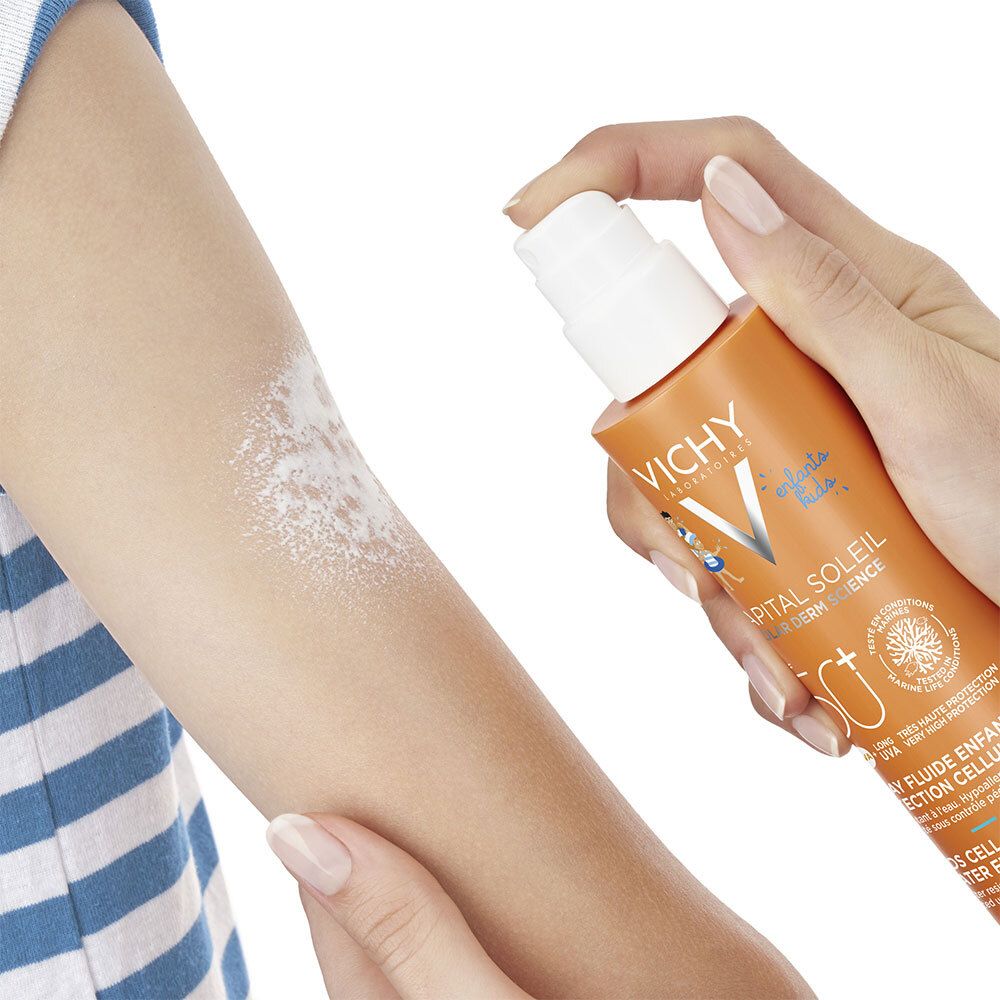 Bras vaporisé avec de la crème solaire. Le spray est visible. Flacon orange.