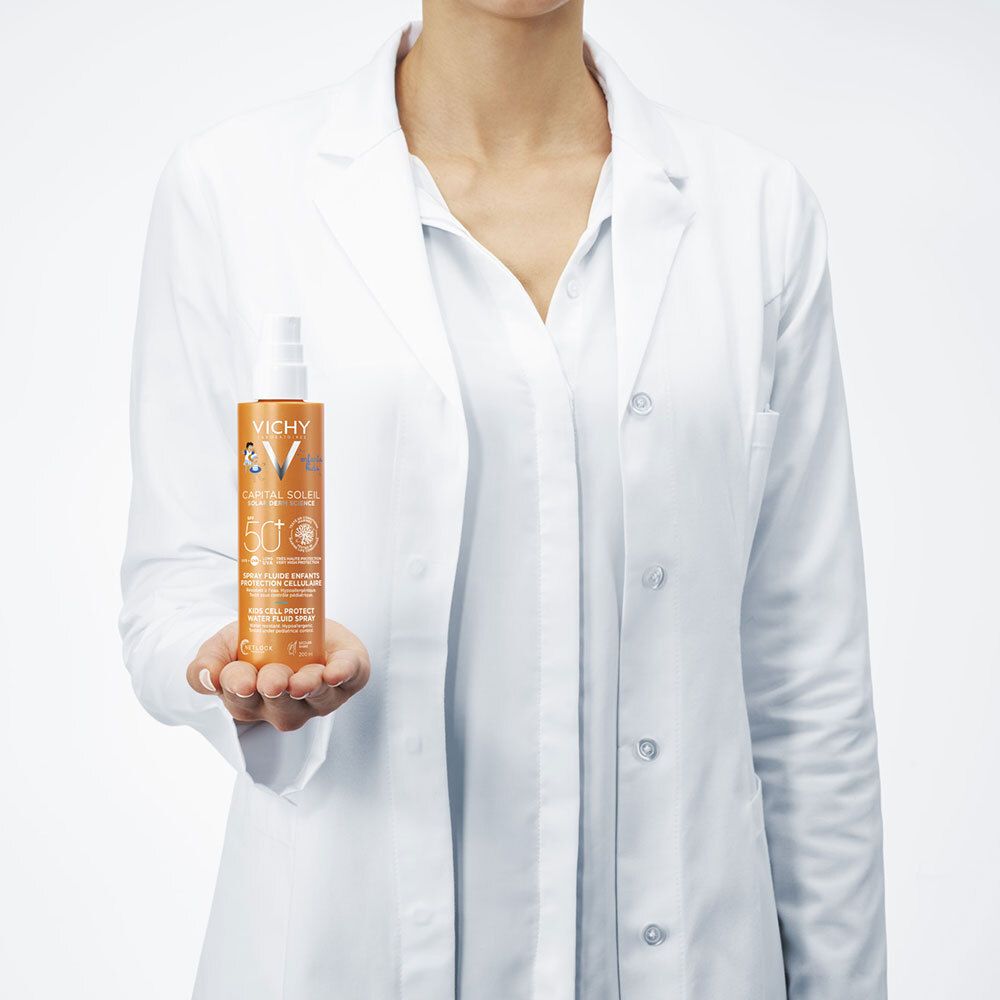 Personne en blouse blanche tenant un flacon de spray solaire. Orange.